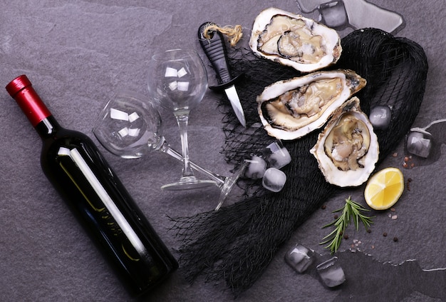 Frische Austern mit einer Flasche Wein auf einer schwarzen Steinoberfläche