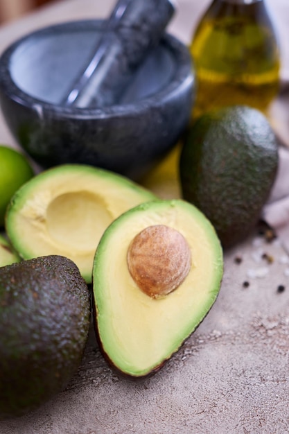 Frische Avocado halbiert und Marmormörser auf grauem Betontisch