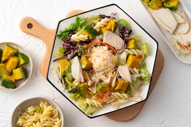 Foto frische avocado-salatschüssel mit geschnittenem hühnerfleisch und rotini in einem teller auf weißem tischhintergrund