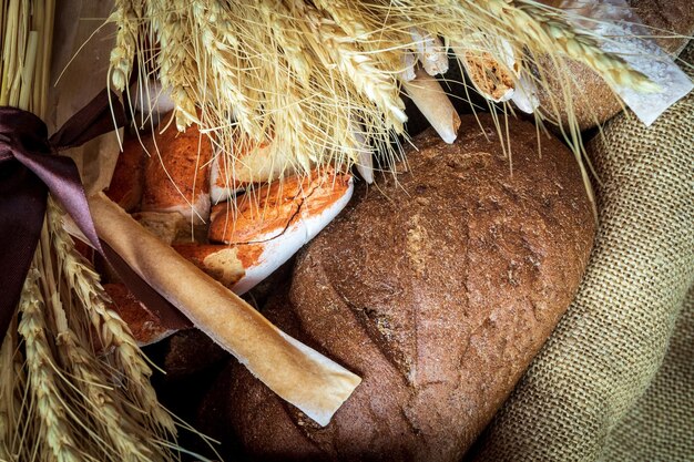 Foto frische backwaren in einem korb mit burlap-tuch und weizenbündeln im rustikalen stil