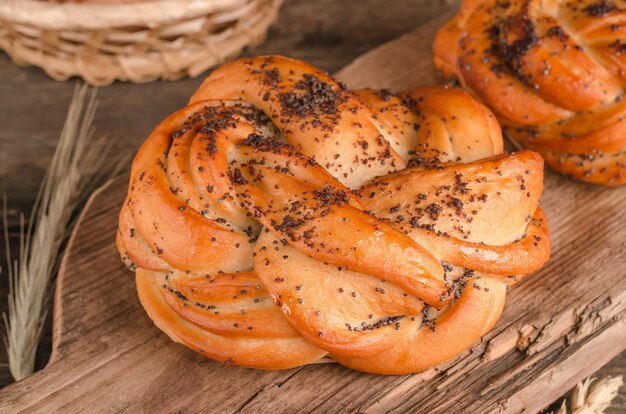 Frische Backwaren Weidenbrötchen mit Mohn auf Holzuntergrund