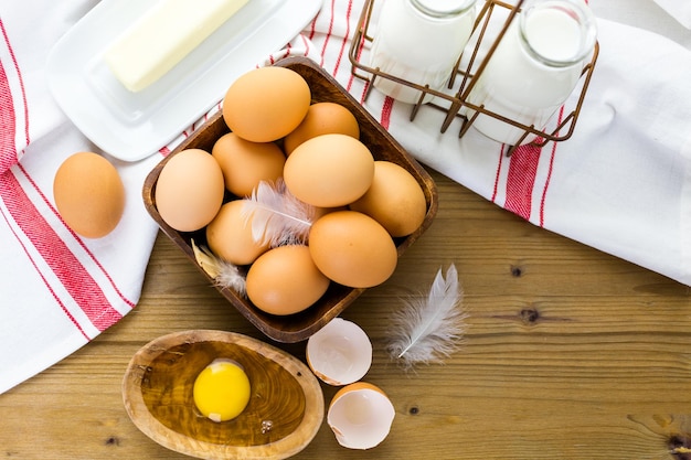 Frische Bauerneier, Milch und Butter auf Holztisch.