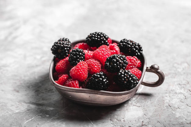 Frische Beeren Himbeeren, Brombeeren auf einem grauen Kunsthintergrund. Gesundes Essen, Sommerbeeren, Abnehmen.