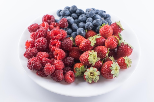 Frische Beeren, Himbeeren, Erdbeeren und Blaubeeren in der Platte lokalisiert auf Draufsicht des weißen Hintergrundes