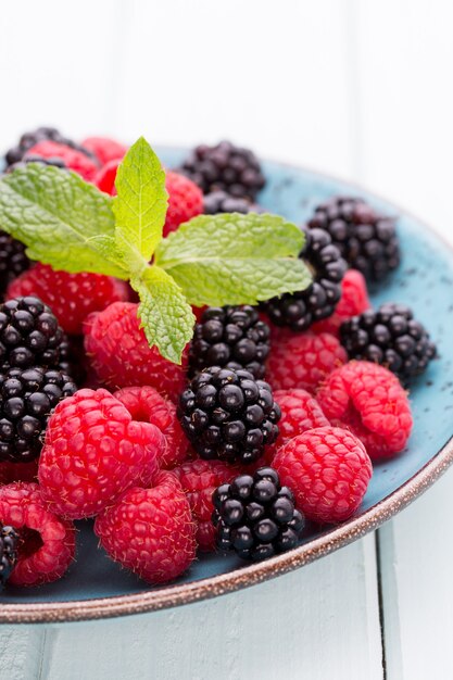 Frische Beeren in einer Platte auf einem hölzernen Hintergrund