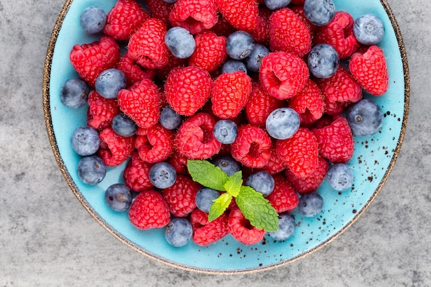 Frische Beeren in einer Platte auf einem hölzernen Hintergrund