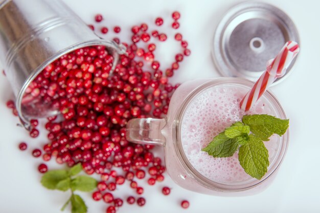 Frische Beeren von Preiselbeeren und Beerenshakes auf weißem Tisch. Smoothie-Konzept für gesunde Ernährung