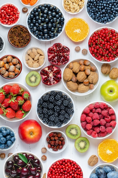 Frische Beerenfrüchte Nüsse auf weißem Holzhintergrund das Konzept der gesunden Ernährung enthält v