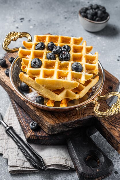 Frische belgische Waffeln mit Blaubeere und Sirup in der Pfanne Grauer Hintergrund Ansicht von oben