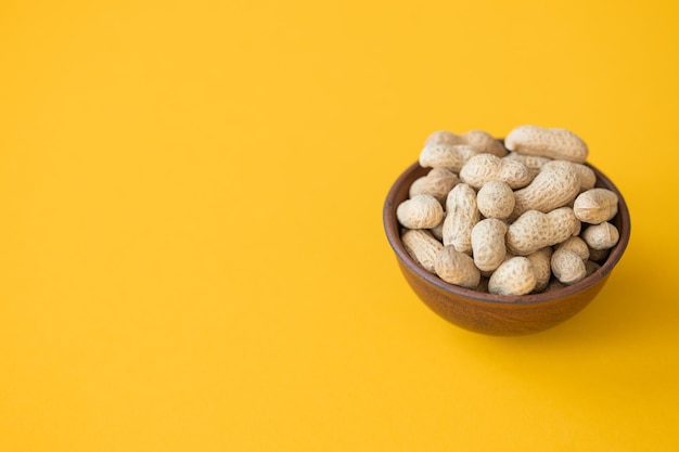 Frische Bio-Erdnüsse in der Schüssel auf gelbem Hintergrund