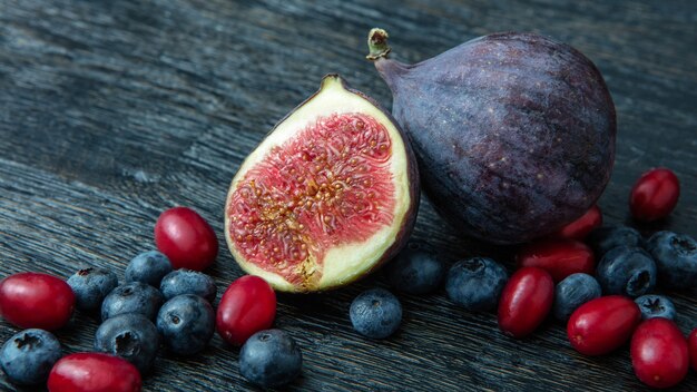 Frische Bio-Feigen, Hartriegel, Blaubeeren und Pflaumen auf Holztisch.