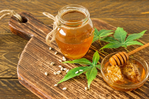 Frische Bio-Honew mit tieferen und Cannabisblättern und -samen auf Holztisch. Gesunde Ernährung alternative Medizin.