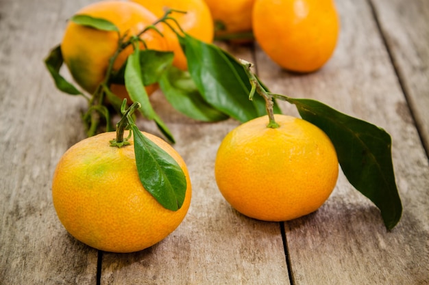 Frische Bio-Mandarinen mit Blättern auf rustikalem Holzhintergrund