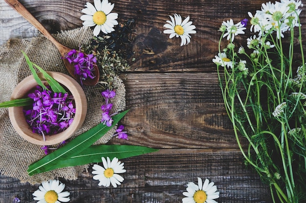 Frische Blätter und Blüten von Ivan-Tee oder Weidenröschen auf Holzhintergrund kopieren das Raumkonzept von Heilpflanzen und Volksmedizin
