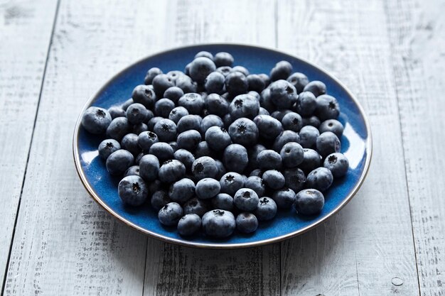 Frische Blaubeeren auf blauem Teller auf Holztisch