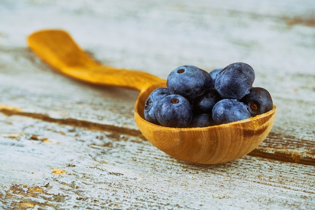 Frische Blaubeeren im hölzernen Löffel über Holztisch