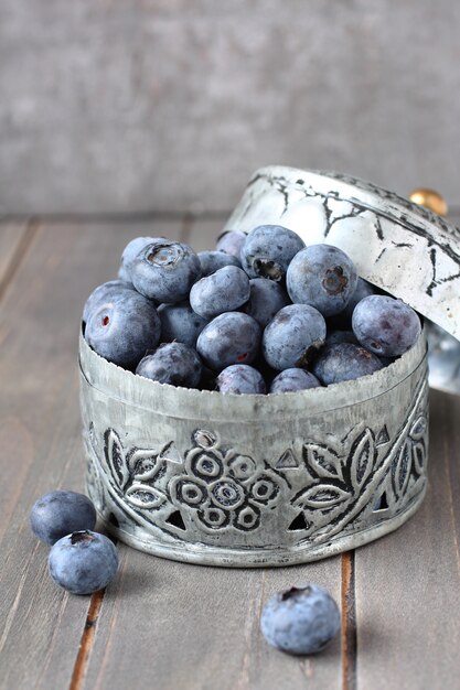 Frische Blaubeeren in der kleinen empfindlichen Metallschatulle auf hölzernem Hintergrund