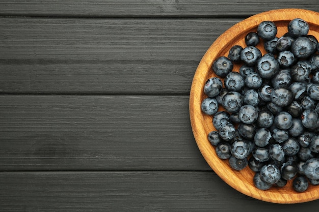 Frische Blaubeeren in Holzschale auf schwarzem Hintergrund Konzept einer gesunden und diätetischen Ernährung von oben