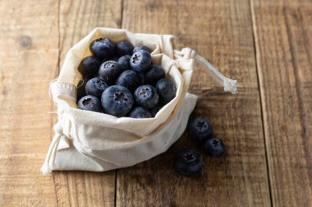 Frische Blaubeeren in umweltfreundlicher Stoff-Textiltasche, rustikaler Holzhintergrund, Null-Taille-Konzept