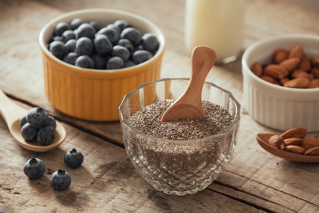 Frische Blaubeeren, Mandel- und Chiasamen mit Milch auf Holzbrett. Ideales gesundes Frühstückskonzept.