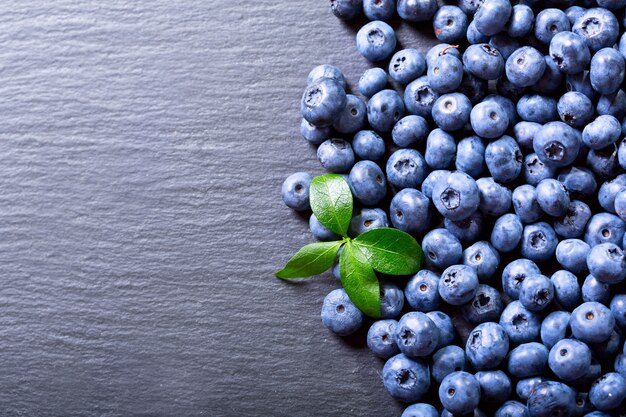 Frische Blaubeeren mit Blatt auf dunklem Tisch, Draufsicht