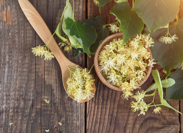 Foto frische blumen von linden oder lindenherzen auf einem holztisch und in einer holzschale