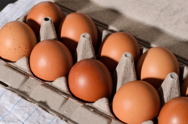 Frische braune Eier auf einem rustikalen, hölzernen, schwarzen, dunklen Hintergrund in einem Kasten