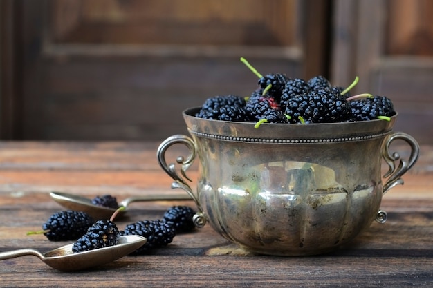 Frische Brombeeren in einer silbernen Schüssel auf rustikalem hölzernem Hintergrund.