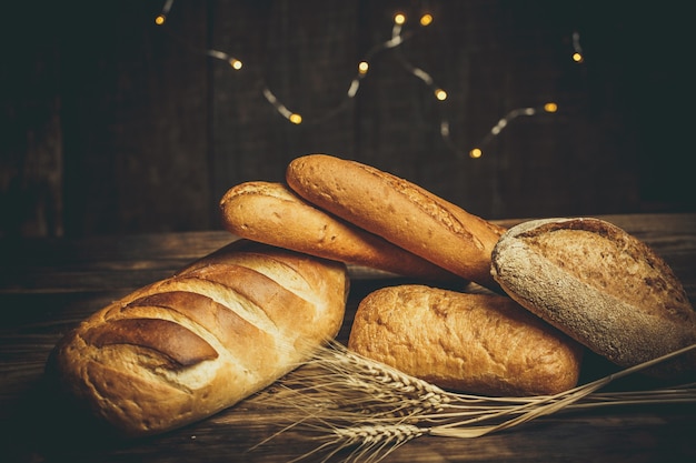 Frische Brote mit Weizen und Gluten auf einem Holztisch