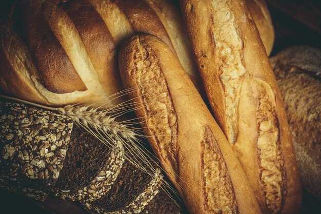 Frische Brote mit Weizen und Gluten auf einem Holztisch