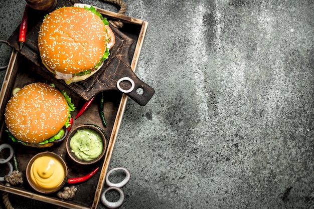 Frische Burger mit Rindfleisch und Gemüse auf einem alten Tablett. Auf einem rustikalen Hintergrund.