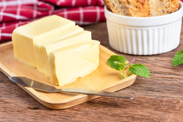 Foto frische butter schnitt mit messer auf hölzerner platte und brot.