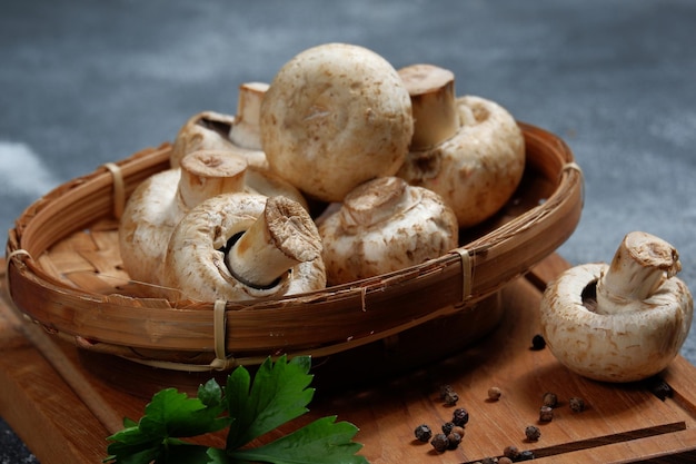 frische Champignons im Bambuskorb auf Holzbrett