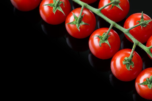 Frische Cherry-Tomaten auf schwarzem Hintergrund Bund frischer Cherry-Tomaten auf schwarzem Hintergrund