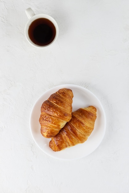 Frische Croissants auf einem weißen Teller mit einer Tasse Kaffee