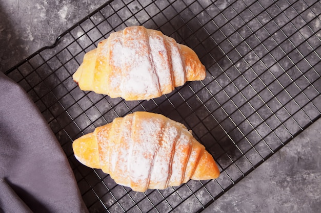 Frische Croissants Brötchen auf dem Backblech und eine Tasse Kaffee in der Nähe.