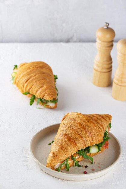 Frische Croissants-Sandwiches mit Lachs-Fisch-Frischkäse-Gurke und Arugula auf einem Leuchttisch