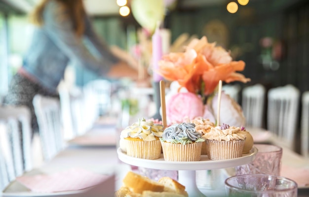 Frische Cupcakes mit Schlagsahne und devorativem Blumenglasur, serviert auf einem Teller am Partytisch weddi