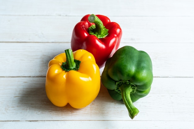 Frische dreifarbige Paprika auf weißem Holz