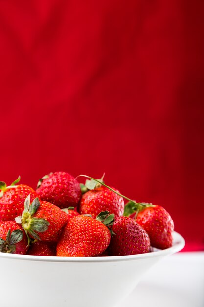 Frische Erdbeere in der weißen Platte auf rotem Hintergrund