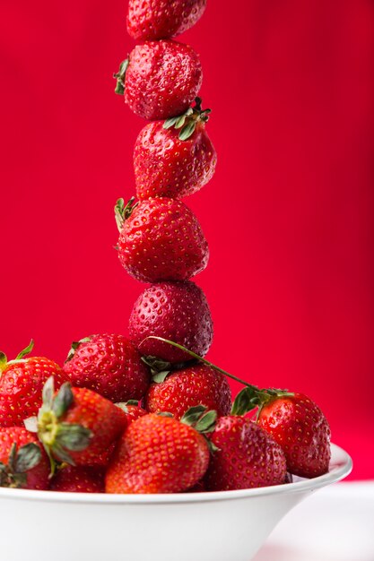 Frische Erdbeere in der weißen Platte auf rotem Hintergrund