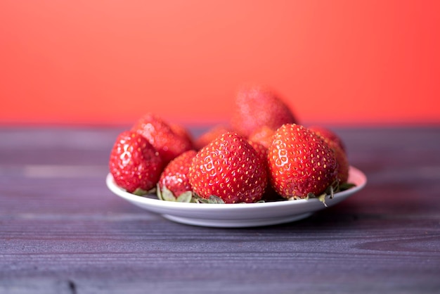 Frische Erdbeeren auf einem weißen Teller auf dunklem Holzhintergrund