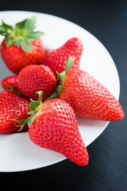 Frische Erdbeeren auf Platte auf schwarzem Hintergrund