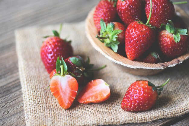 Frische Erdbeeren auf Sack, rote reife Erdbeere auf Holzuntergrund