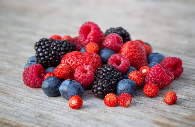 Frische Erdbeeren, Blaubeeren, Brombeeren und Himbeeren auf Holzhintergrund