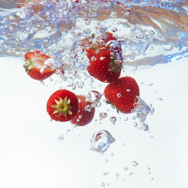 Frische Erdbeeren fielen mit Spritzer ins Wasser