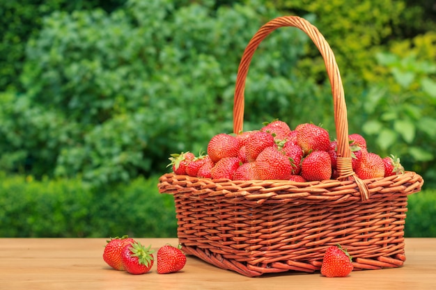 Foto frische erdbeeren in einem korb auf holztisch im garten