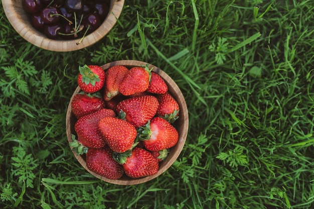 Frische Erdbeeren in Holzschale auf grünem Hintergrund