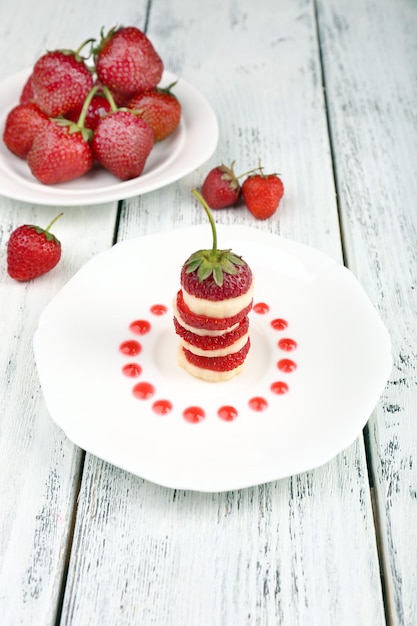 Foto frische erdbeeren mit banane am spieß auf platte auf tisch nahaufnahme