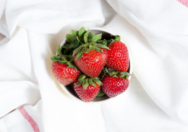Frische Erdbeeren und Saft auf weißem Stoff. flach legen.